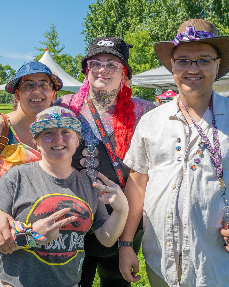 LGBTQ+ customers at a pride festival wearing Proud Zebra pride pins and a branded Proud Zebra lanyard, from the queer-owned Canadian brand
